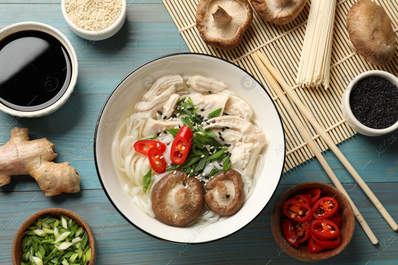 Photo of Delicious ramen with meat and ingredients on light blue wooden table, flat lay. Noodle soup