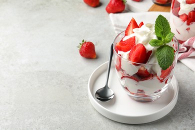 Photo of Delicious strawberries with whipped cream served on light grey table. Space for text