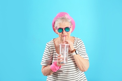 Portrait of cool grandmother with drink on color background