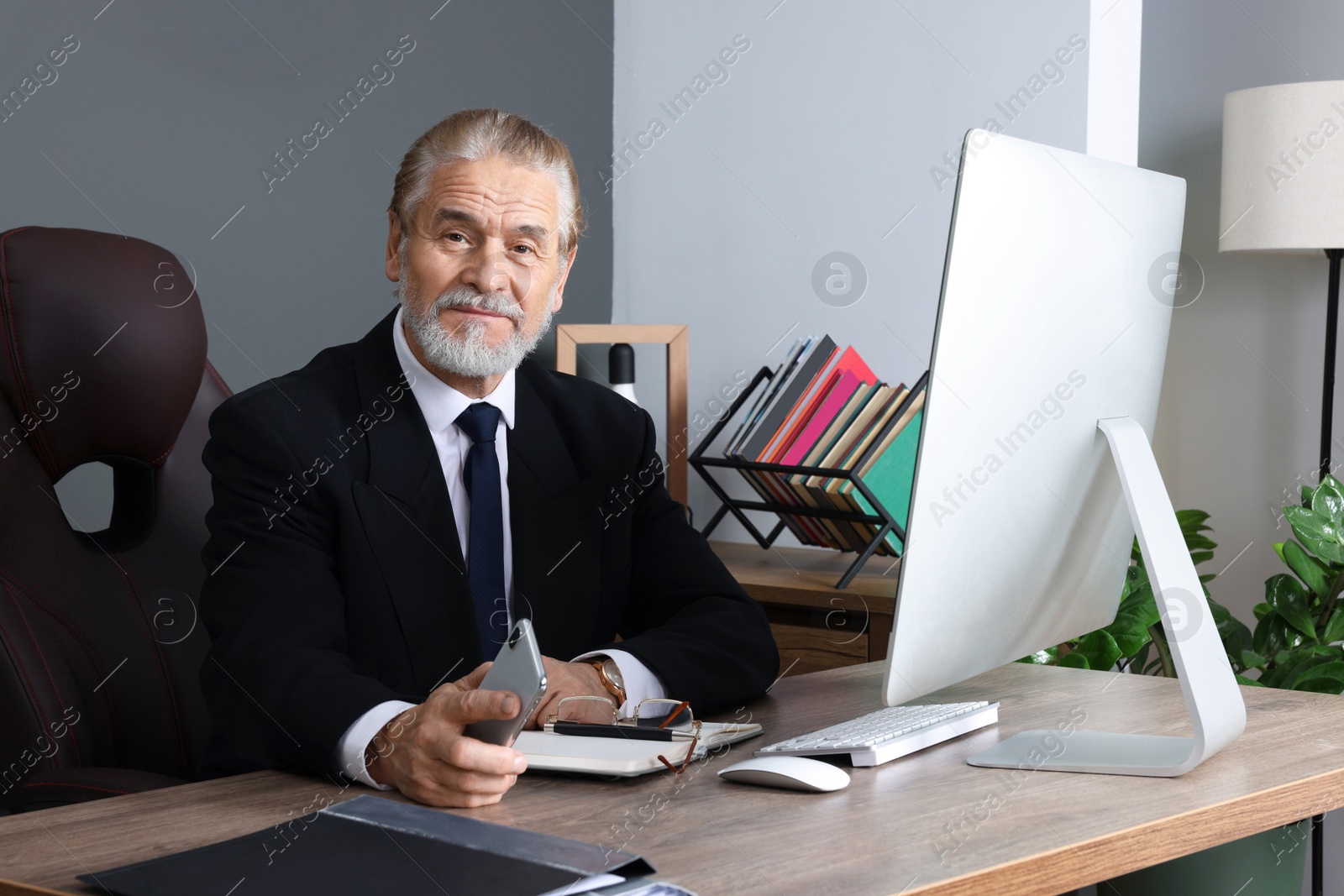 Photo of Happy senior boss working in his office