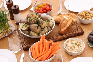 Photo of Healthy vegetarian food, glasses, cutlery and plates on wooden table