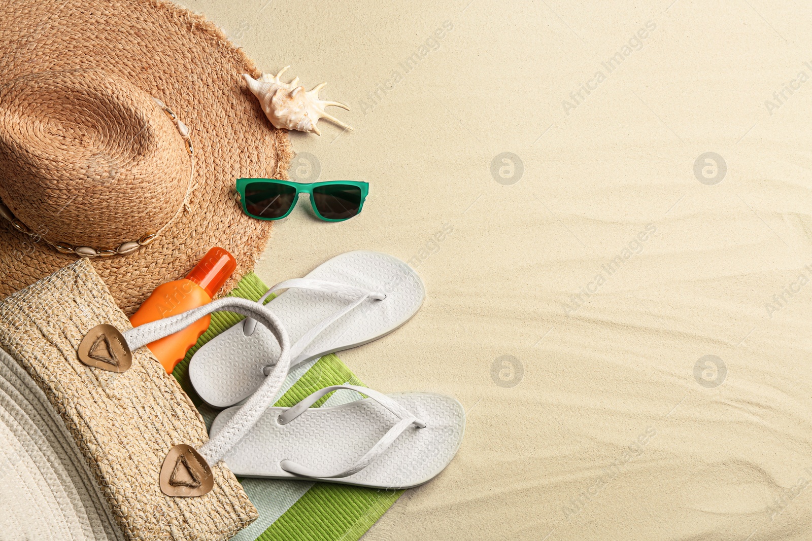 Photo of Different beach accessories on sand, flat lay. Space for text