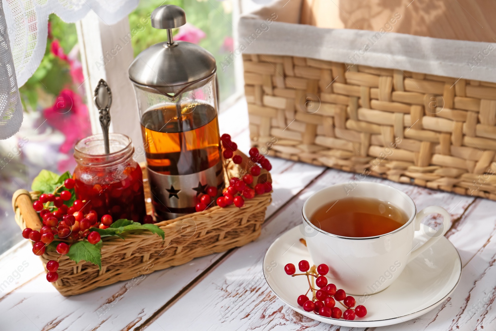 Photo of Cup of hot drink and viburnum berries on white wooden table indoors