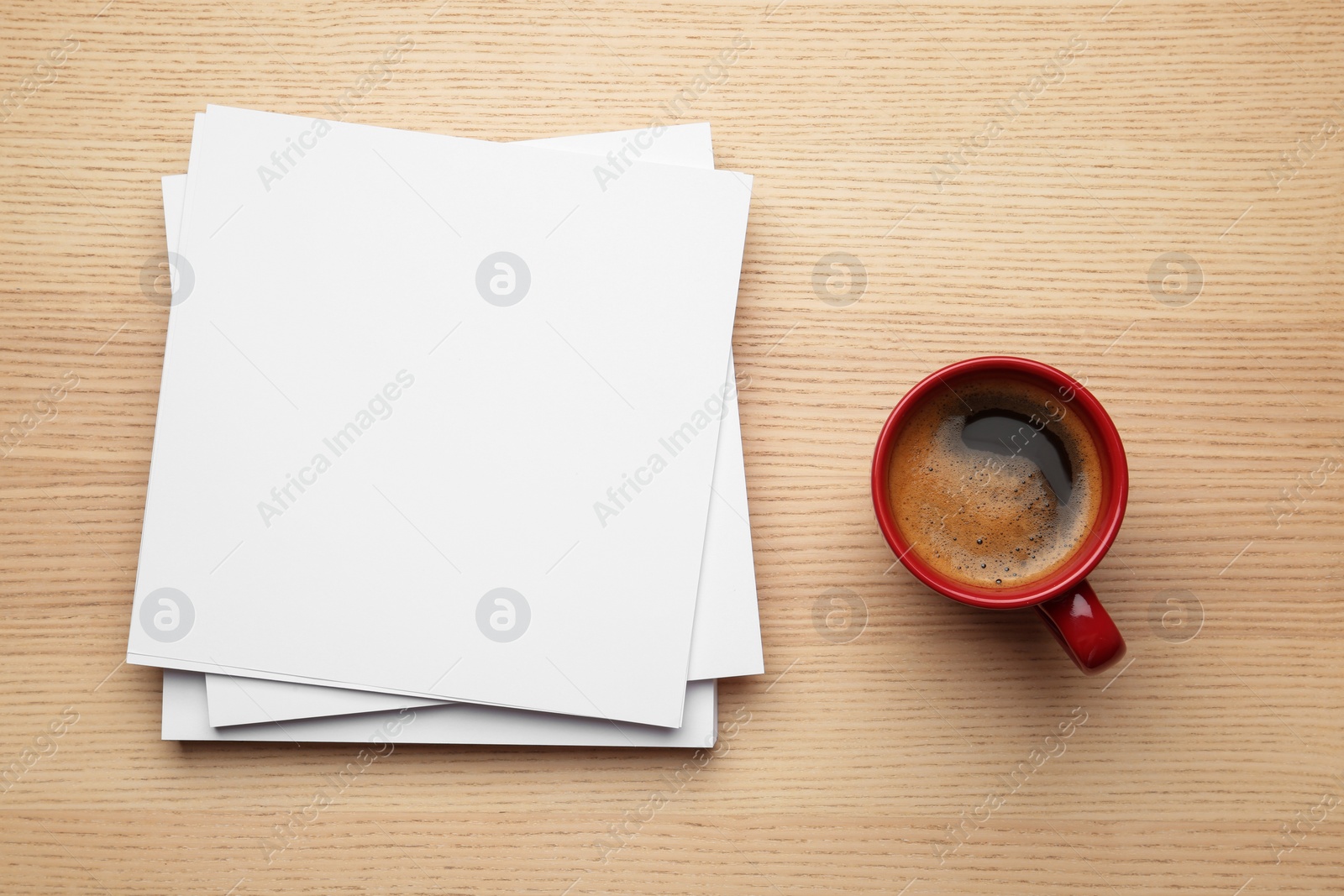 Photo of Blank paper sheets for brochure and cup of coffee on wooden background, flat lay. Mock up