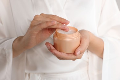 Photo of Woman taking hand cream from jar, closeup