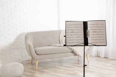 Photo of Note stand with music sheets indoors. Space for text