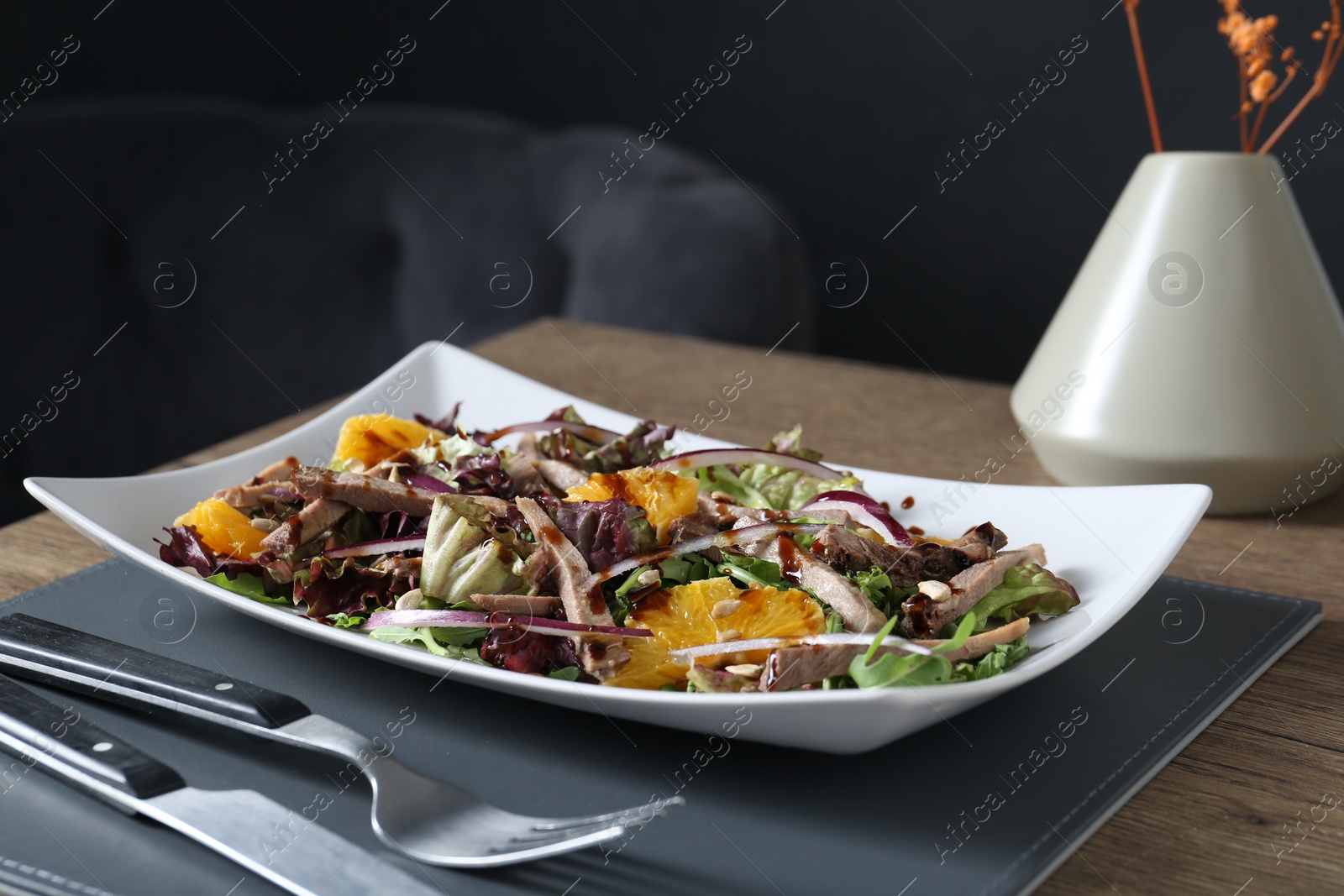 Photo of Delicious salad with beef tongue, orange and onion served on wooden table