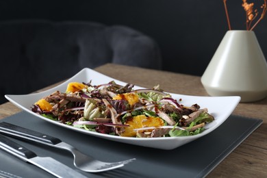 Photo of Delicious salad with beef tongue, orange and onion served on wooden table
