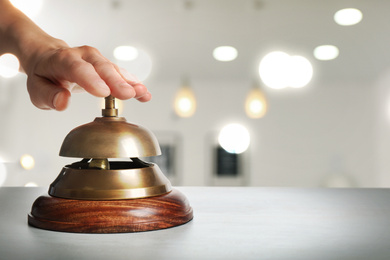 Man ringing hotel service bell on blurred background, closeup. Space for text