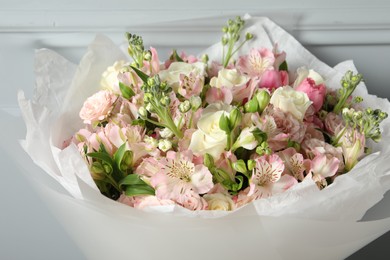 Photo of Beautiful bouquet of fresh flowers near wall, closeup