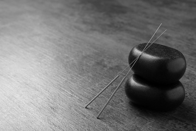 Acupuncture needles and stones on dark table