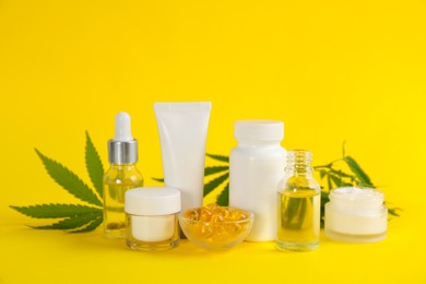Photo of Composition with CBD oil, THC tincture and hemp leaves on yellow background