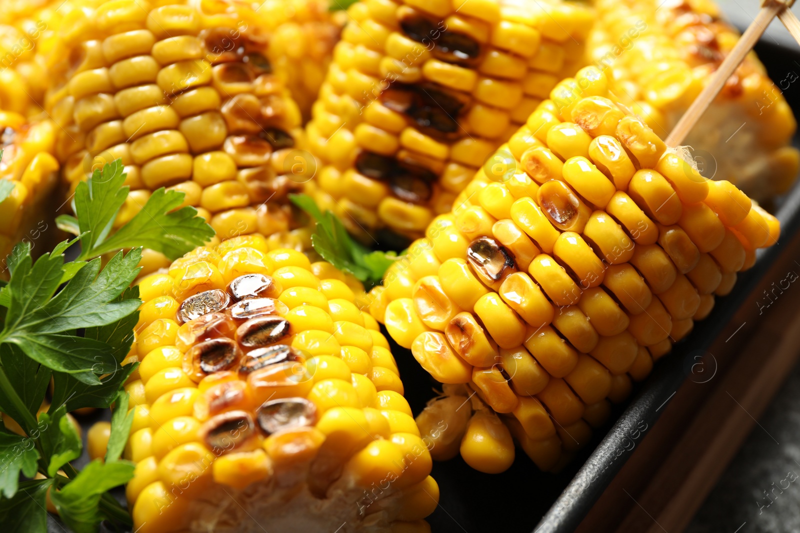 Photo of Tasty grilled corn with parsley, closeup view