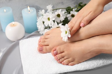 Woman with neat toenails after pedicure procedure on grey silky fabric, closeup