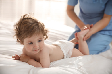 Photo of Orthopedist examining cute little baby on bed