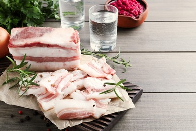 Photo of Tasty salt pork with rosemary and pepper on wooden table, space for text