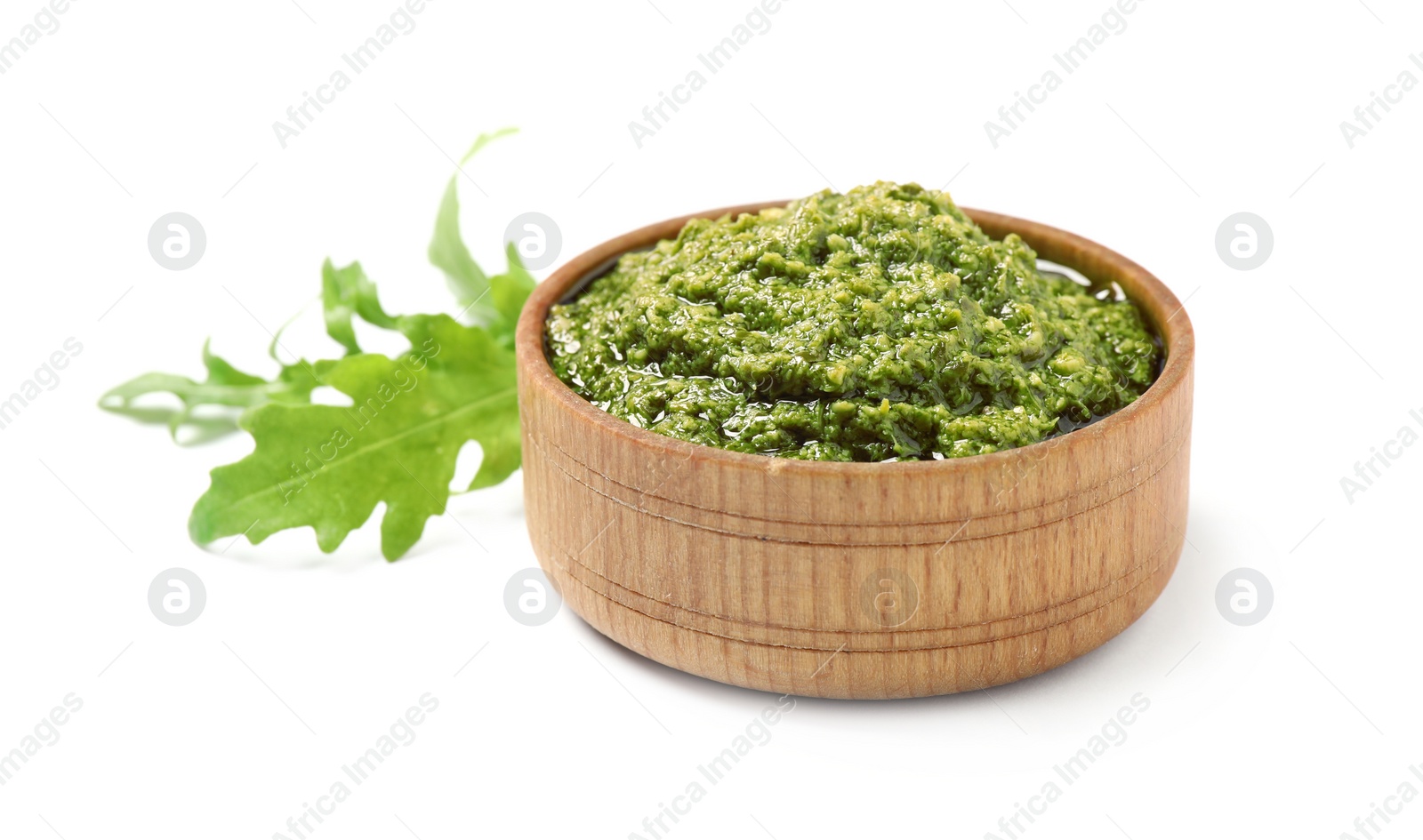 Photo of Bowl of tasty pesto and arugula on white background