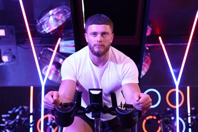 Young man training on exercise bike in fitness club