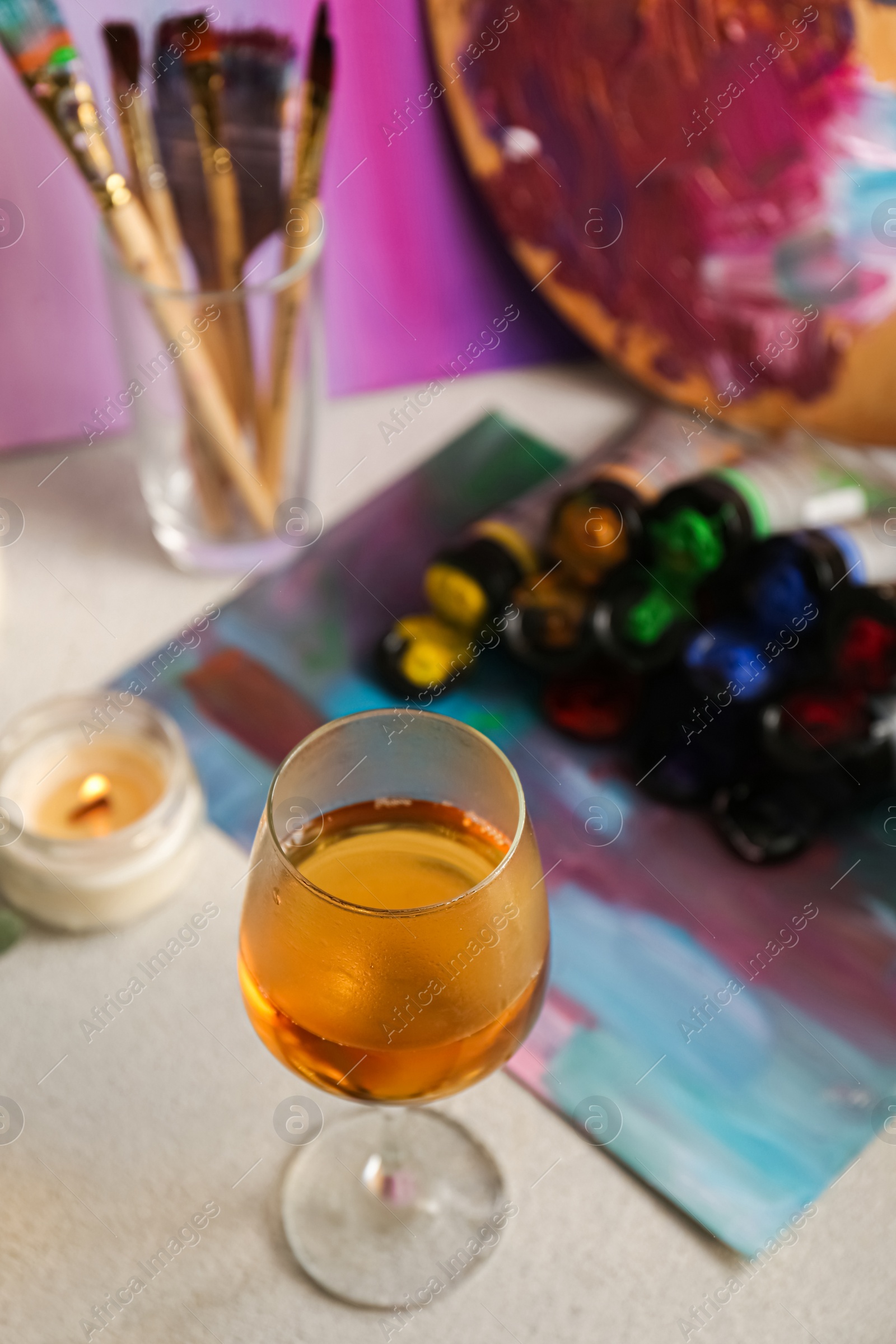 Photo of Glass of tasty wine, colorful paints and canvas, above view. Space for text