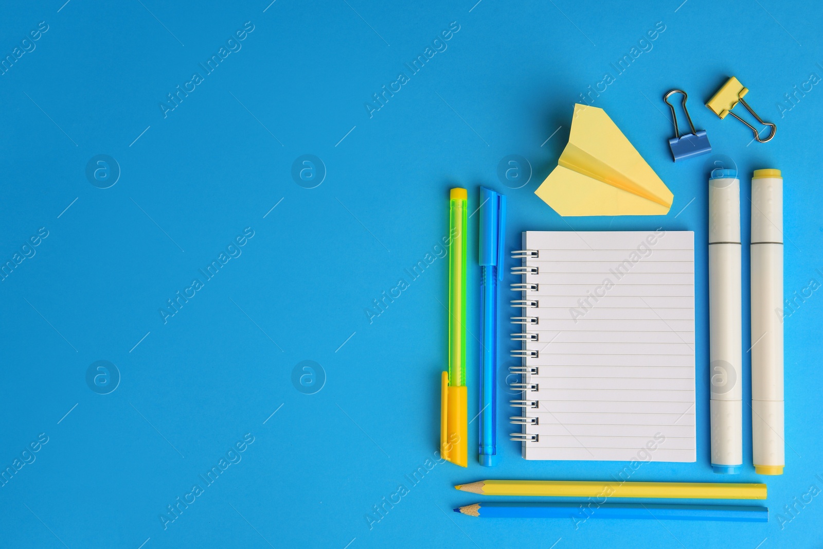 Photo of Paper plane and different school stationery on light blue background, flat lay with space for text. Back to school