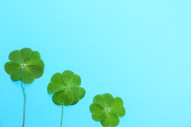 Photo of Beautiful green four leaves clover on light blue background, flat lay. Space for text
