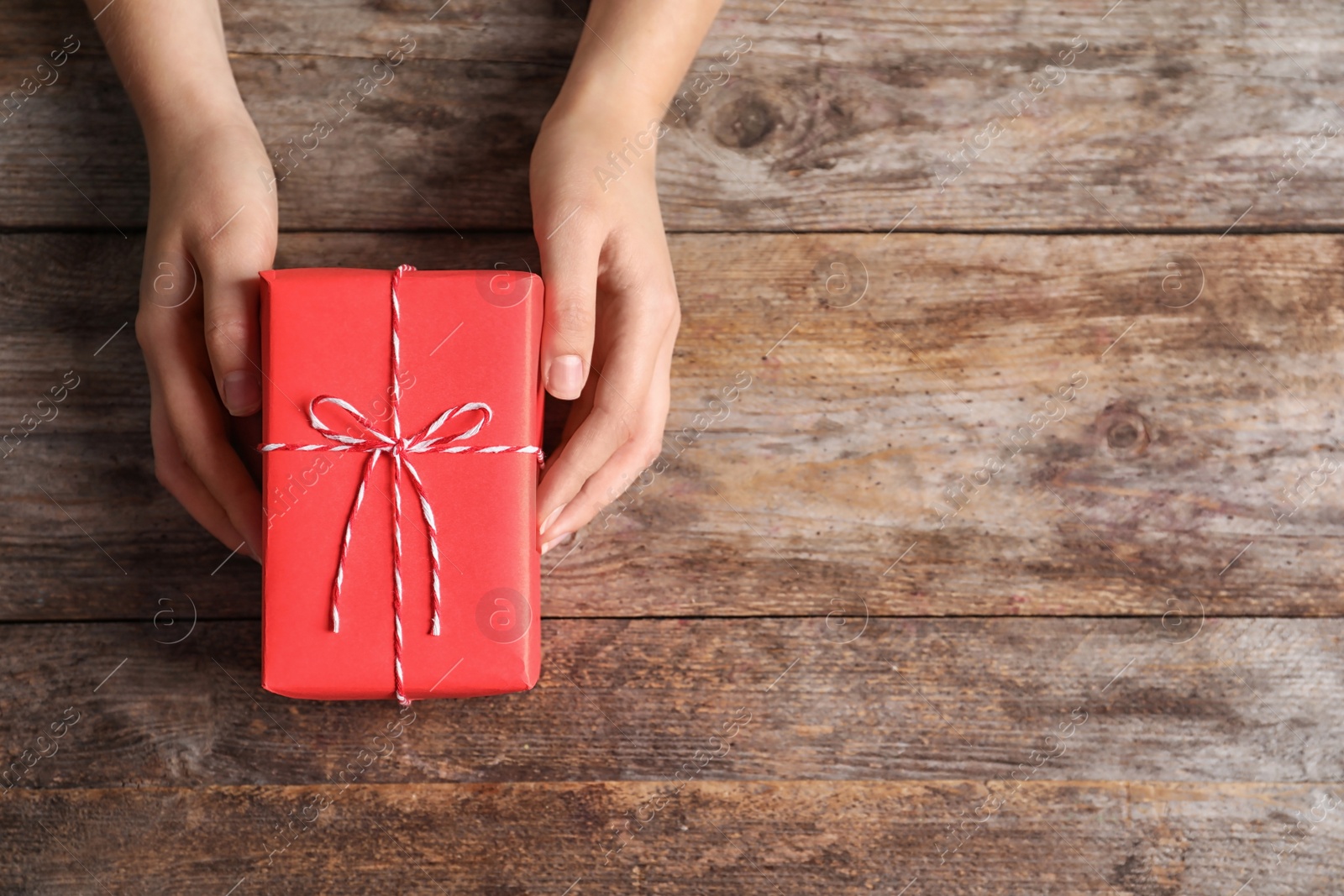 Photo of Woman with beautiful gift box on wooden background, top view