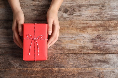 Woman with beautiful gift box on wooden background, top view