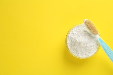 Photo of Bowl of tooth powder and brush on yellow background, flat lay. Space for text