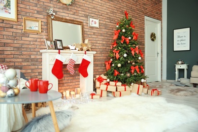 Photo of Room interior with beautiful Christmas tree and gifts near decorative fireplace