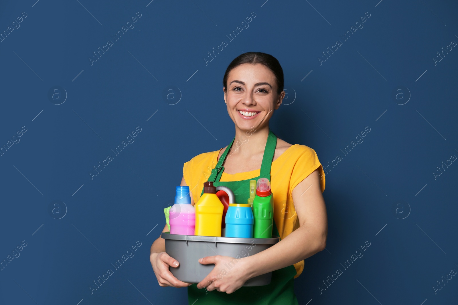 Photo of Woman with basin of detergents on color background