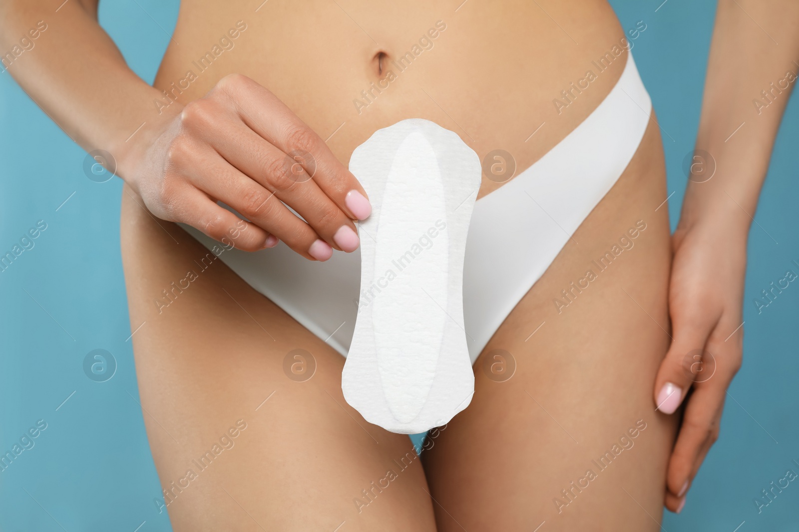 Photo of Woman in white panties with menstrual pad on light blue background, closeup