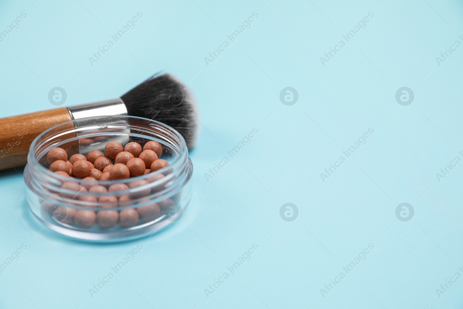 Photo of Face powder balls and brush on light blue background, space for text