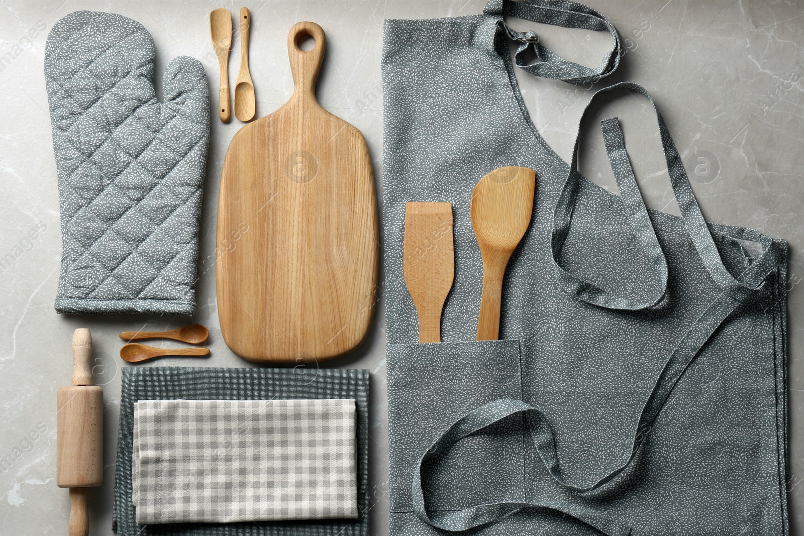 Photo of Kitchen napkins, apron and different utensils on light grey table, flat lay