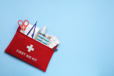 Photo of First aid kit on light blue background, top view. Space for text