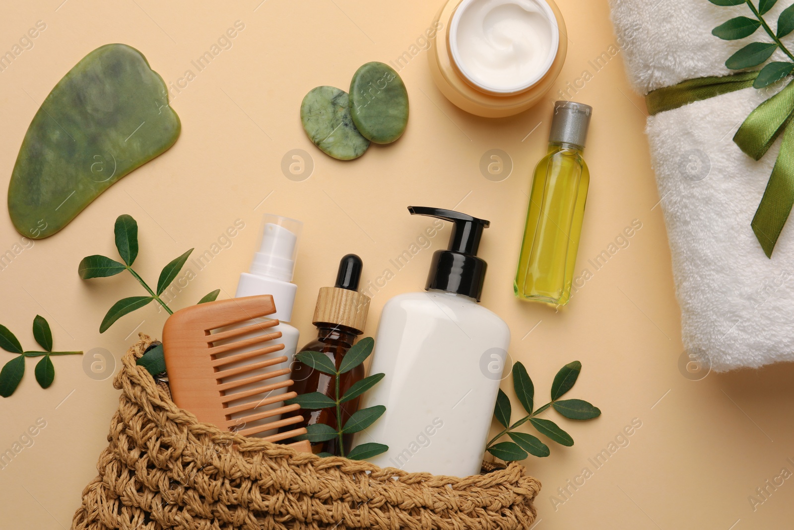 Photo of Compact toiletry bag with different cosmetic products, spa stones and towel on beige background, flat lay