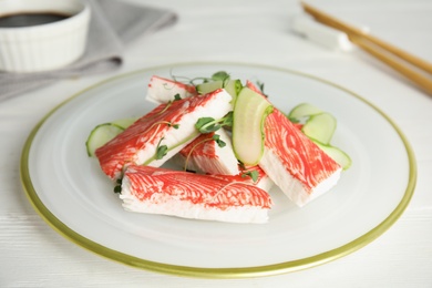 Fresh crab sticks with cucumber served on white wooden table, closeup