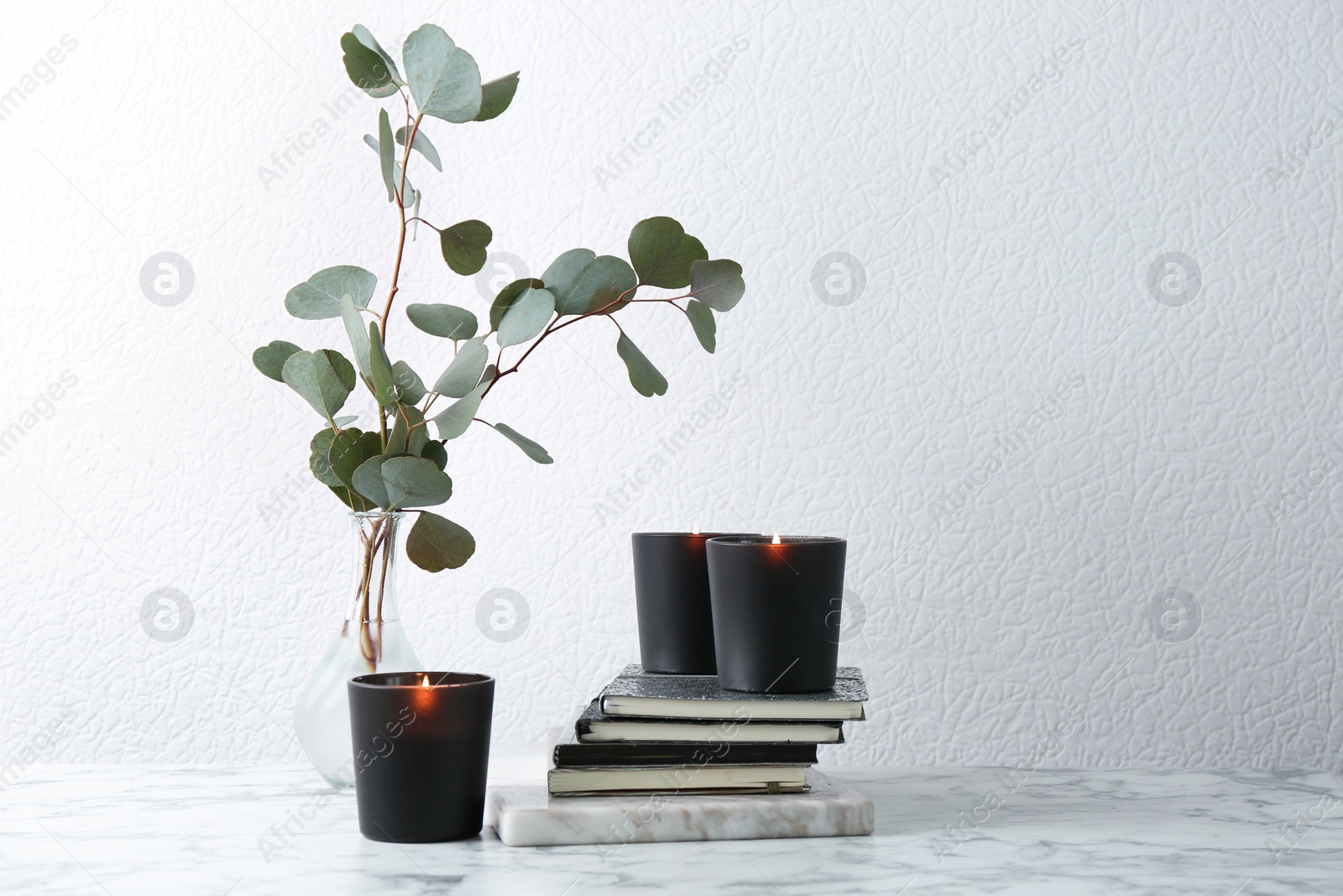 Photo of Composition with notebooks, burning candles and green branches on table