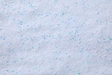 Photo of Laundry powder detergent with color granules as background, top view