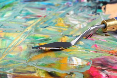 Photo of Abstract colorful acrylic paint and spatula, closeup view