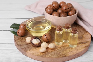 Delicious organic Macadamia nuts and cosmetic oil on white wooden table