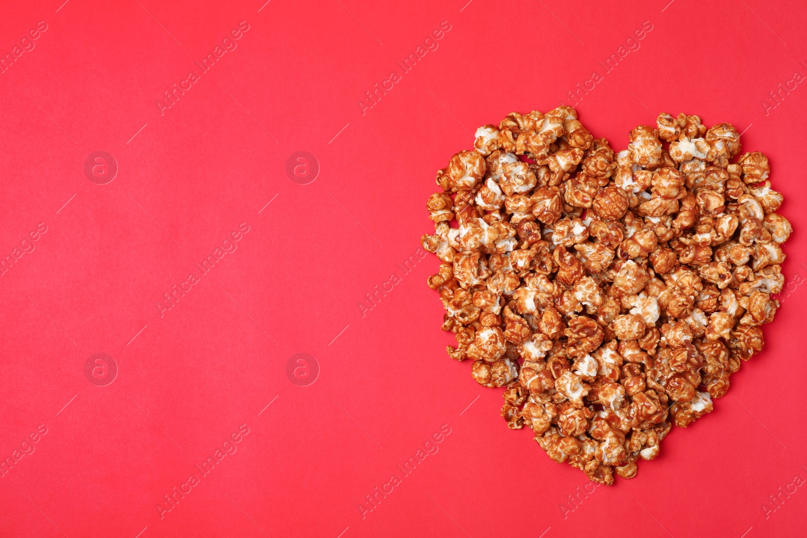 Photo of Heart made of caramel popcorn on color background, top view. Space for text