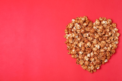 Heart made of caramel popcorn on color background, top view. Space for text