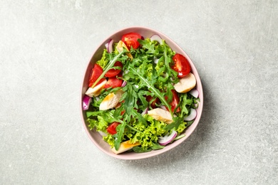 Photo of Delicious salad with chicken, arugula and tomatoes on grey table, top view