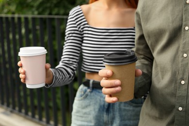 Coffee to go. Couple with paper cups outdoors, closeup