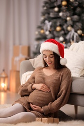 Happy pregnant woman with Christmas gift box at home. Expecting baby