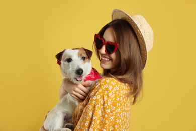 Photo of Young woman with her cute Jack Russell Terrier on yellow background. Lovely pet