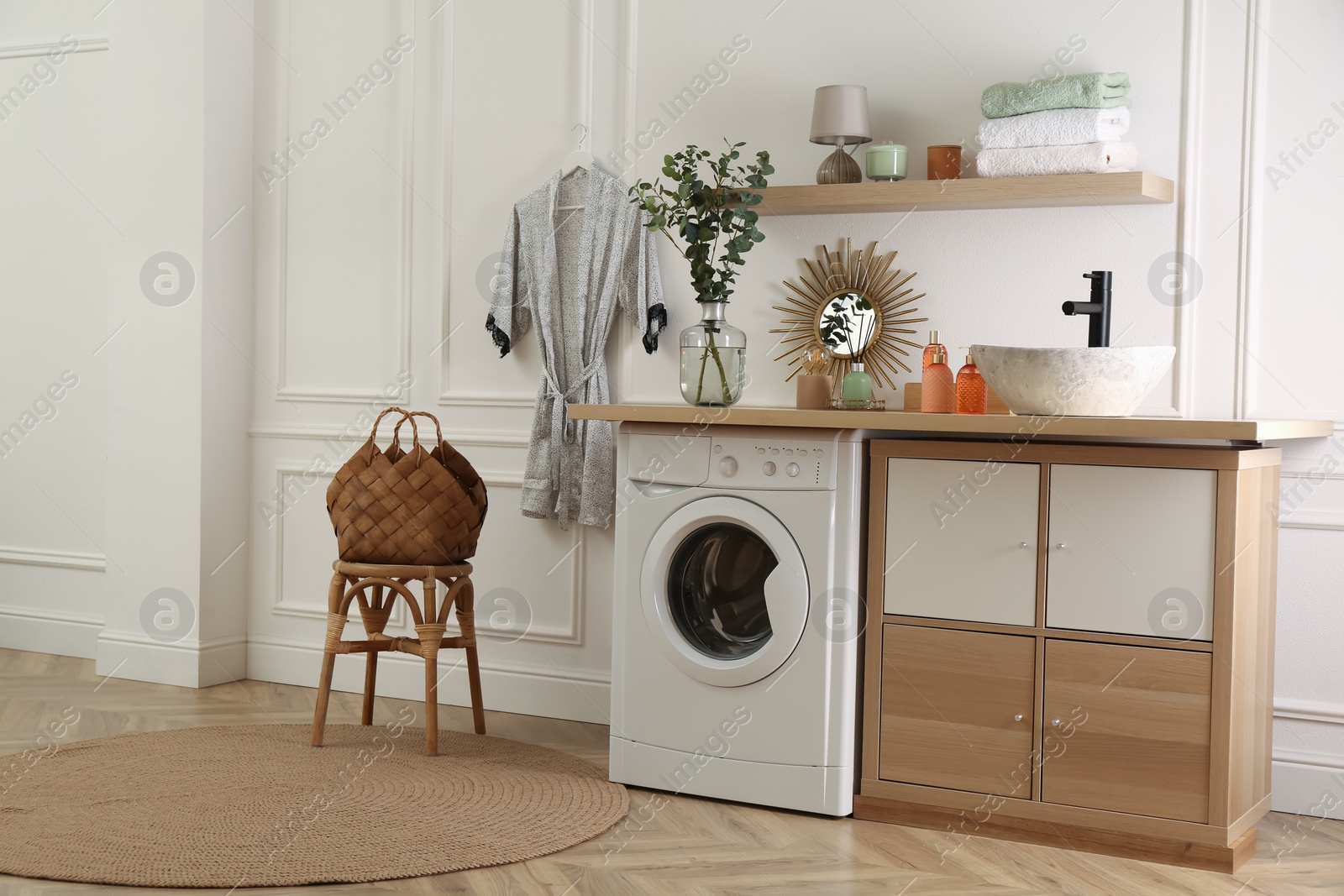 Photo of Laundry room interior with modern washing machine and stylish vessel sink on countertop