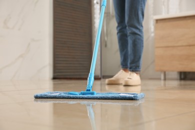 Woman cleaning floor with mop indoors, closeup