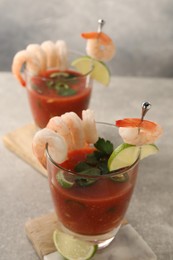 Tasty shrimp cocktail with sauce in glasses and lime on light grey table, closeup