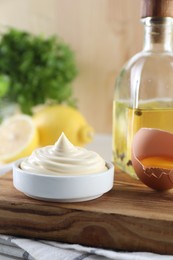 Photo of Fresh mayonnaise sauce in bowl and ingredients on table